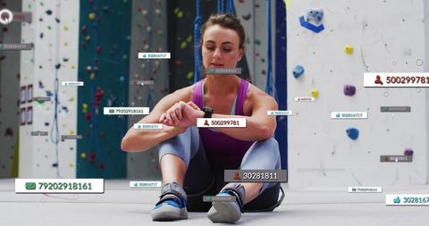 Connected Female Rock Climber Using Smartwatch in Gym