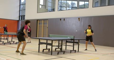 Diverse Athletes Enjoying Ping-Pong Game in Modern Sports Hall