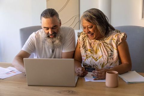 Mature couple reviewing finances online with laptop and credit card