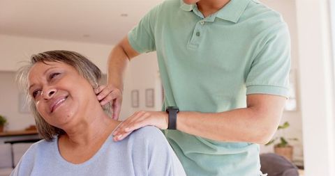 Physiotherapist assisting senior woman with neck and shoulder massage