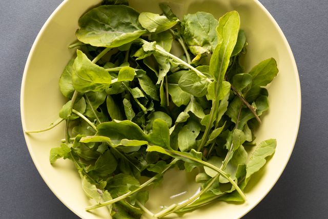 Directly above view of fresh leafy vegetables in bowl on gray background. unaltered, organic food and healthy eating concept.