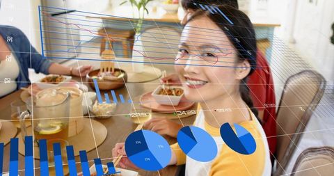 Smiling woman sitting at dining table viewing augmented reality charts and visualizations