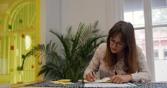 Woman Writing in Notebook at Desk in Modern Workspace - Download Free Stock Images Pikwizard.com