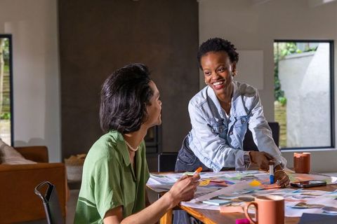 Diverse women collaborating over color swatches and sketches at creative studio table