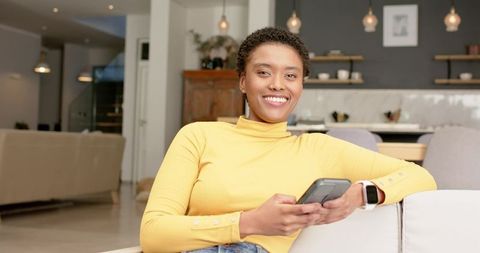 Happy Woman in Yellow Sweater Relaxing with Smartphone and Smartwatch