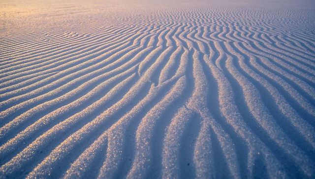 Rippling sand ridges catching golden dawn light on coastal flat abstract texture pattern
