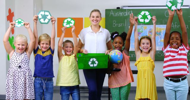 School kids and teacher holding recycling symbols and globe in classroom at school 4k