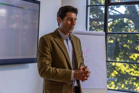 Businessman Presenting in Office with Charts and Graphs