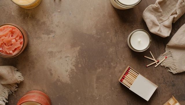 Rustic still life with open matchbox, red matches, candles and jars on worn tabletop