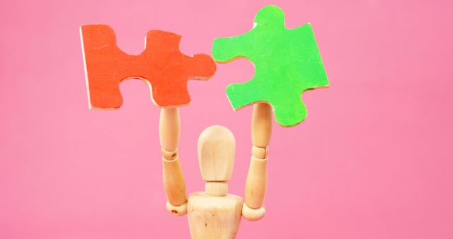 A wooden figure holds up two mismatched puzzle pieces against a pink background, with copy space. It symbolizes the challenge of finding solutions or the concept of mismatched ideas or elements.