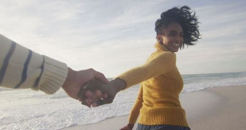 Joyful couple holding hands on sandy beach adventure