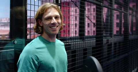 Smiling man in modern gym near glass and metal grid background