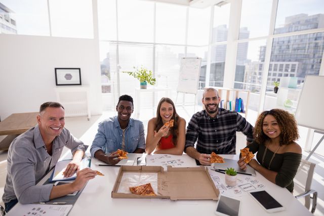 Portrait of executives having pizza in conference room at office