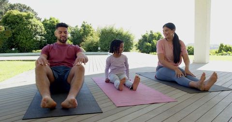 Family enjoys outdoor yoga session on a sunlit patio