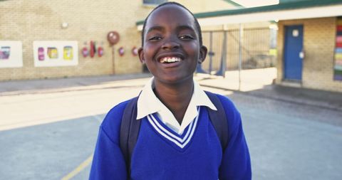 Joyful african schoolboy smiling in playground