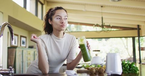 Woman with Vitiligo Savoring Green Smoothie in Modern Kitchen