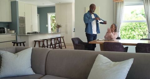 Couple opening mail and celebrating at dining table in modern open-concept home