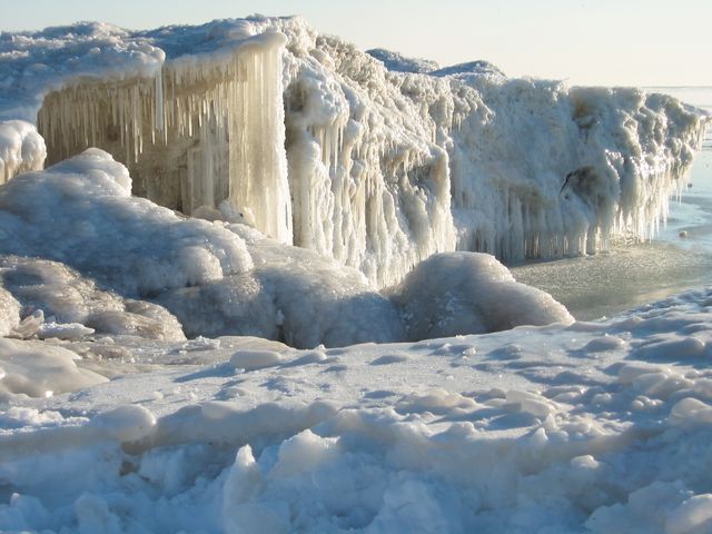 Frozen arctic landscape featuring large icicles and snow-covered rocks, with icy water in the background. Useful for themes related to winter, extreme cold, and natural beauty. Ideal for travel magazines, environmental awareness projects, and seasonal promotional materials.