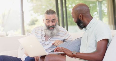 Senior men sharing laptop for fun conversation indoors