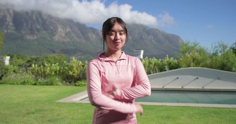 Asian woman stretching in backyard garden with covered pool and mountain view