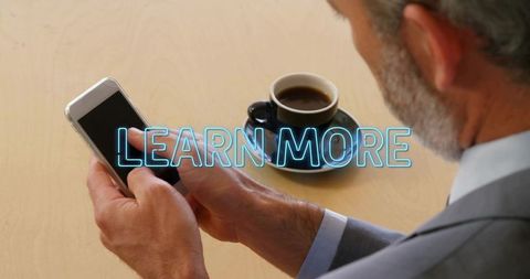 Senior executive using smartphone with neon learn more overlay during coffee break