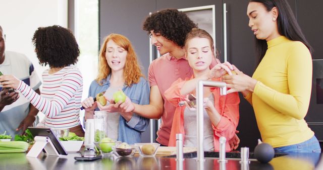 Happy group of diverse friends preparing healthy drink in kitchen together. Spending quality time at home together.