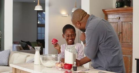 Laughing Father and Daughter Cooking Together in Kitchen