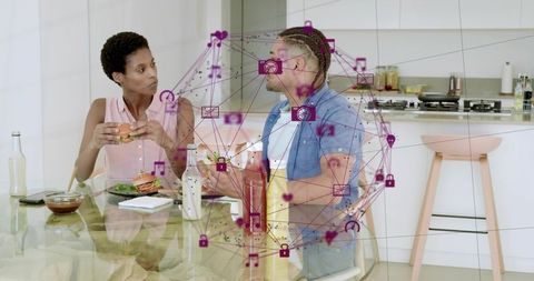 Couple sharing casual meal in modern kitchen with magenta digital network overlay