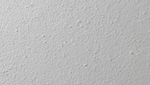 Close-up White Stippled Plaster Wall Texture with Raised Bumps for Interior Backgrounds