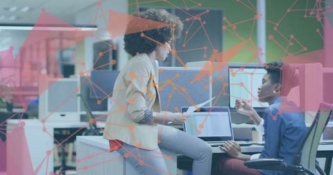 Two Women Professionals Collaborating at Office Desk with Digital Network Overlay