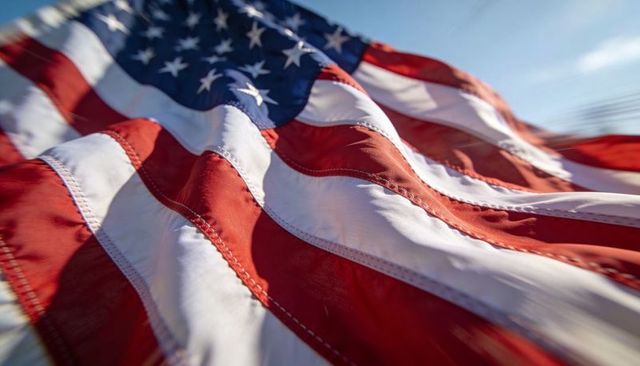 American flag waving close-up showing stitched stars and stripes in sunlight