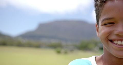 Joyful Child Smiling Outdoors with Mountain Background