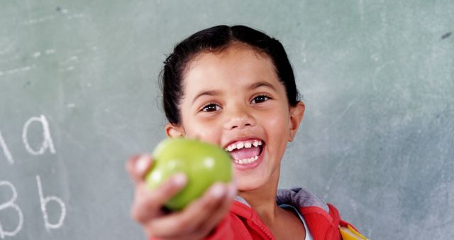 Young Girl Holding Green Apple in Classroom - Download Free Stock Images Pikwizard.com