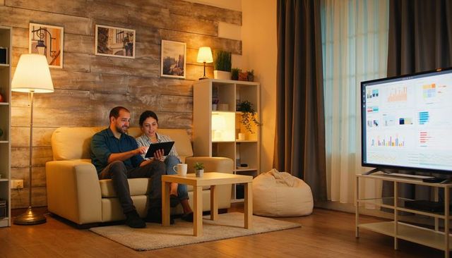 Couple reviewing finances and charts on tablet in cozy modern living room