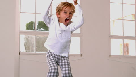 Energetic Boy Jumping in Pajamas Near Window