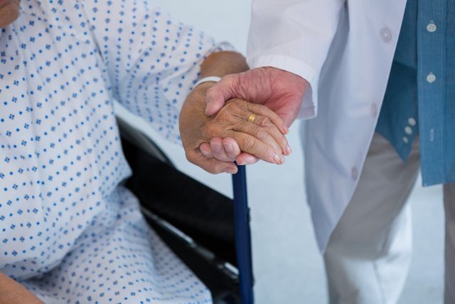 Close-up of doctor consoling senior patient on wheelchair at hospital