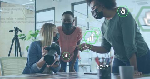 Creative team collaborating with camera and sustainability data overlays in modern office
