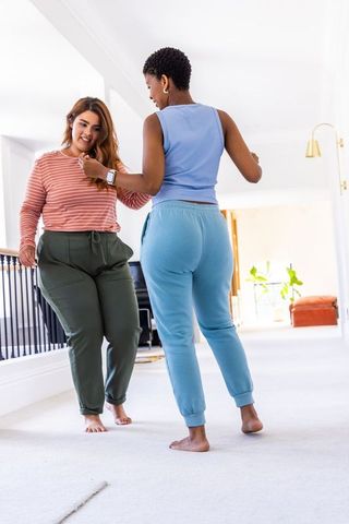 African american friends walking barefoot indoors checking smartwatch in casual athleisure