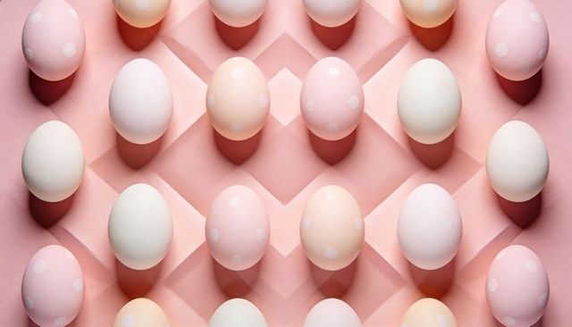 Pastel dotted eggs lining pink grid tray casting soft shadows minimalist decor