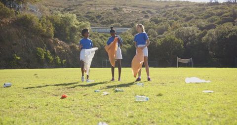 Diverse Children Collecting Litter on Sunny Sports Field