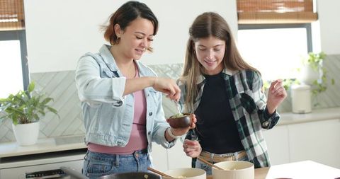 Diverse women preparing meal together in bright modern kitchen island