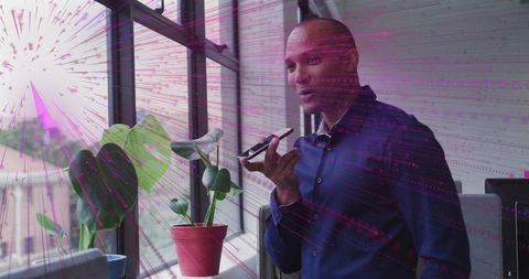 Businessman using smartphone for voice input by modern office window