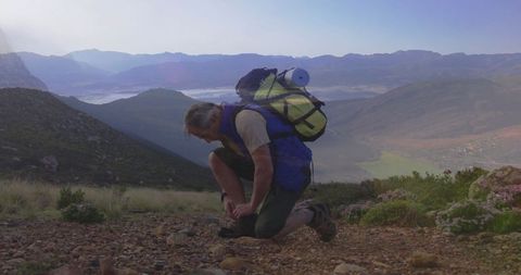 Hiker in mountain wilderness adjusting boot laces
