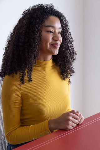 Confident Woman Seated Indoors in Minimalist White Room