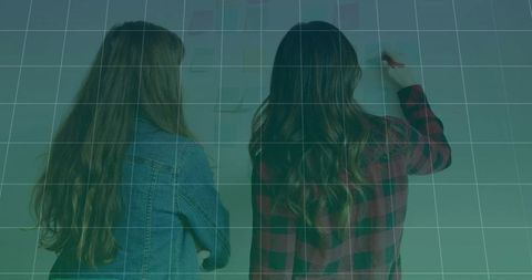 Women collaborating at idea wall writing sticky notes planning project and brainstorming