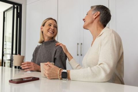 Multigenerational women sharing coffee and laughter at bright modern kitchen island