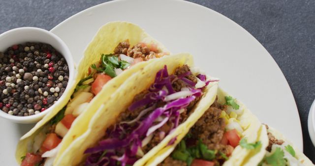 This vibrant image shows fresh and colorful beef tacos filled with assorted vegetables and beef, garnished with red cabbage and cilantro. Ideal for food blogs, recipe websites, culinary magazines, and advertisements promoting Mexican cuisine. Use this engaging image to attract food enthusiasts and highlight the appetizing qualities of traditional homemade tacos.