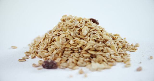 Nutritious granola pile with oats and raisins on white background. Perfect for illustrating diet plans, healthy breakfast ideas, and natural snack options. Suitable for use in food blogs, nutrition websites, and natural product presentations.
