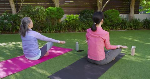 Mother and Daughter Practicing Outdoor Meditation on Lawn