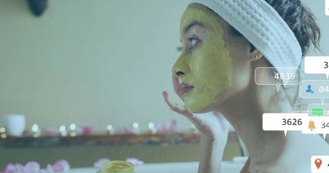 Woman Applying Green Face Mask at Spa Amidst Candles